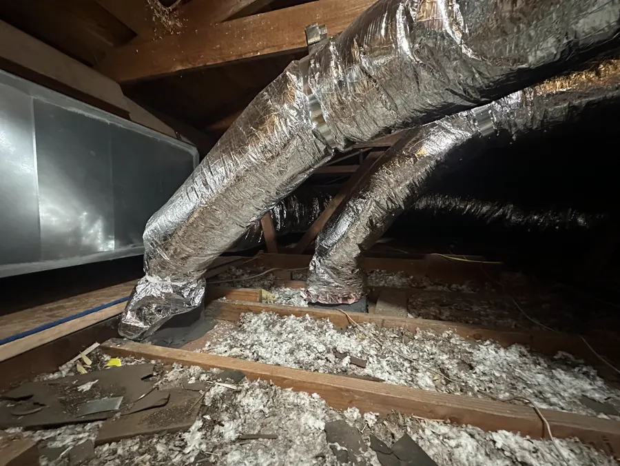 A furnace plenum with new insulated ducts in an attic