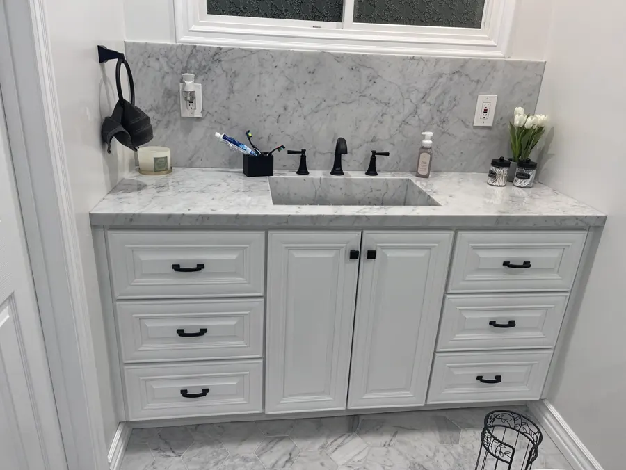 A white shaker vanity with a quartz top and black faucet