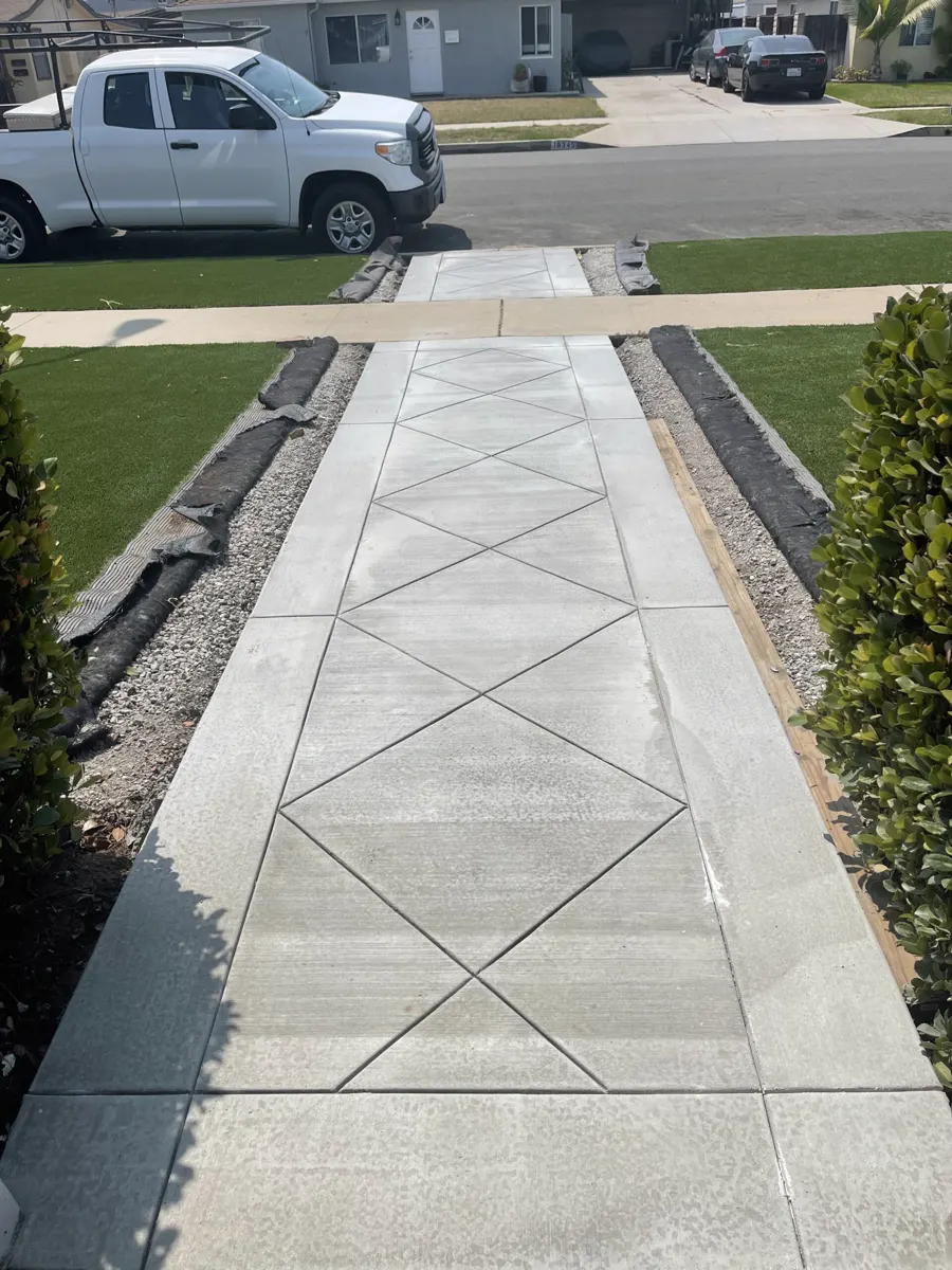 A long front walkway with diamond-pattern control joints