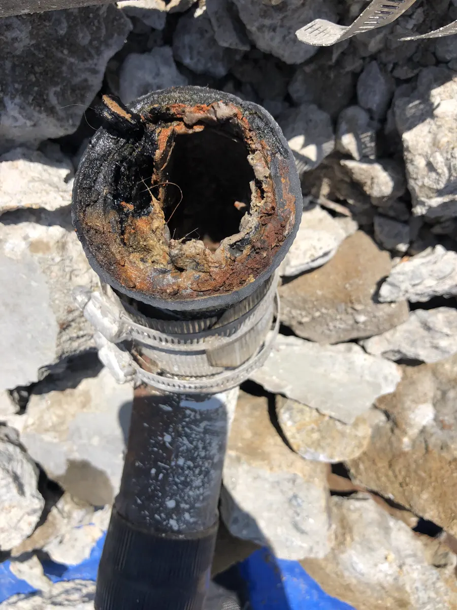 A badly corroded old pipe exposed in rubble
