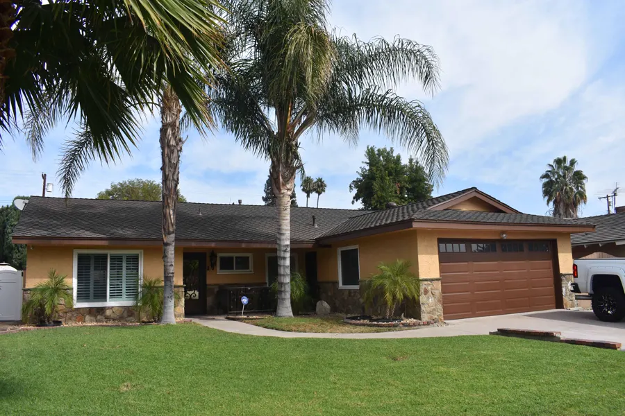 Freshly painted single-story home with palms and a green lawn