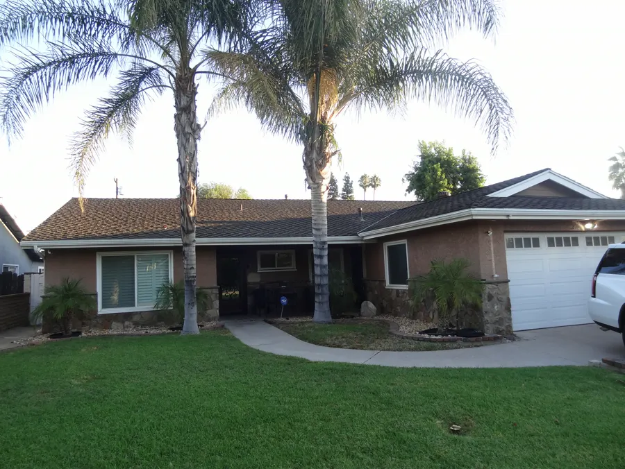 A single-story home with brown stucco, stone veneer and a white garage door