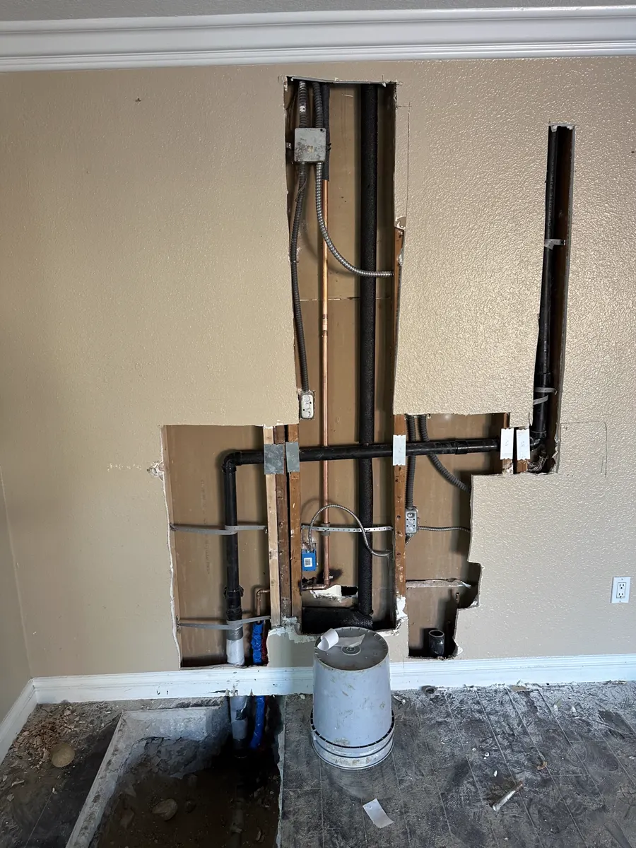 An opened wall with new water lines and a stub-out