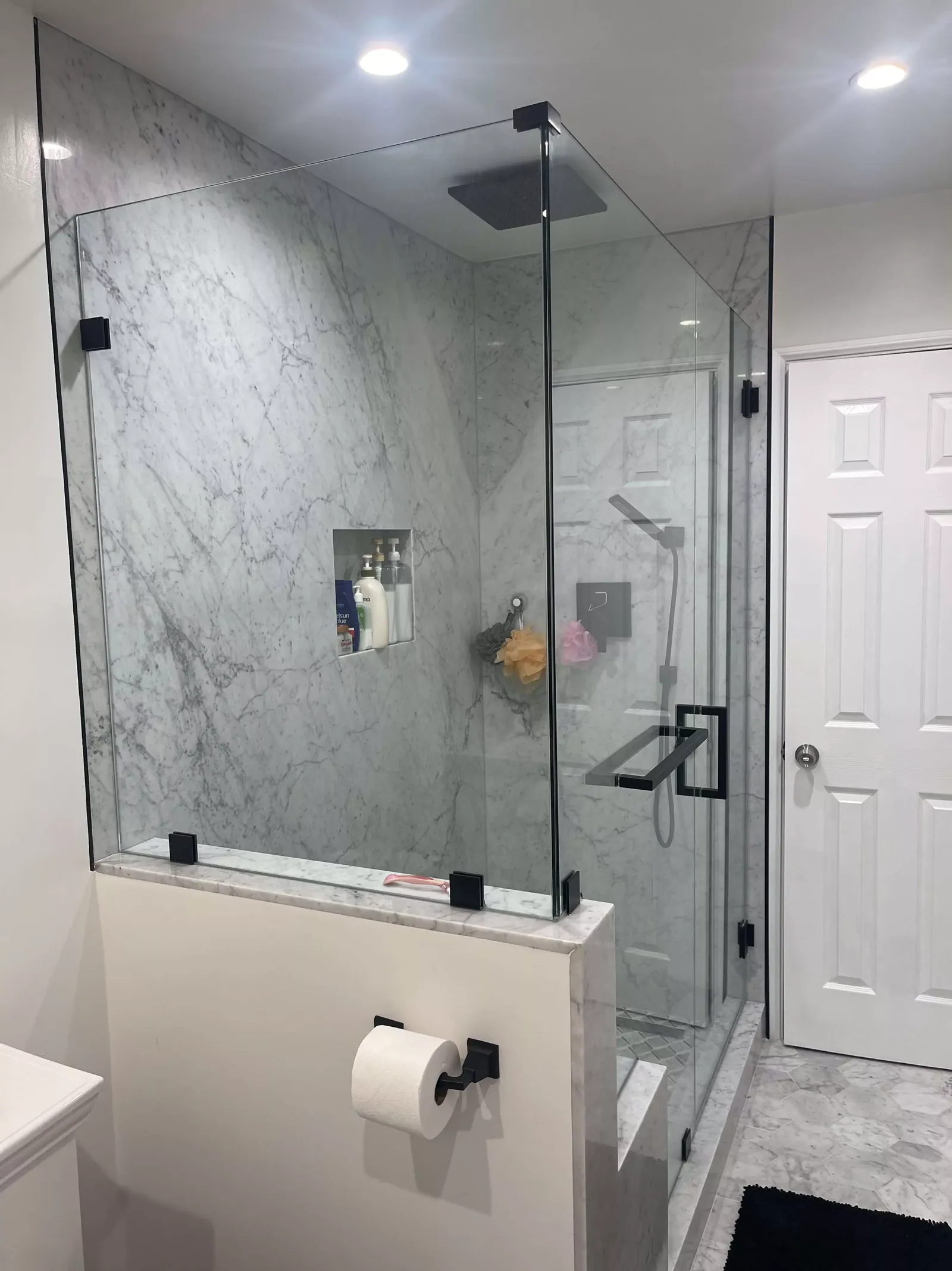 A frameless glass shower with marble-look tile