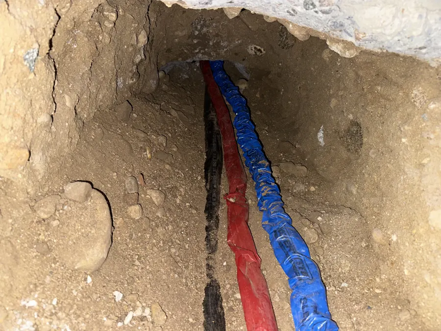 New red and blue supply lines laid in a dirt trench