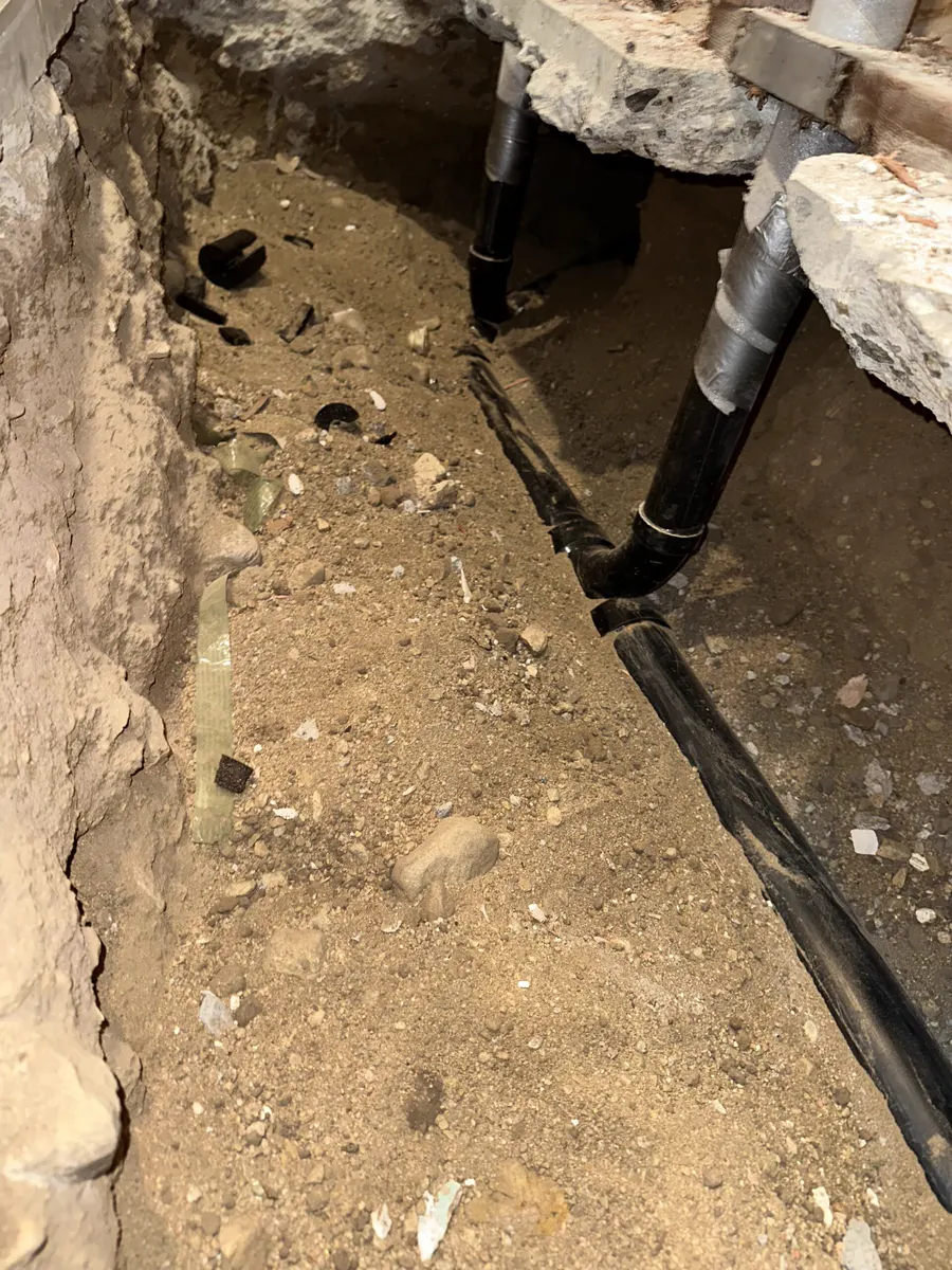 A black drain line in an open dirt trench