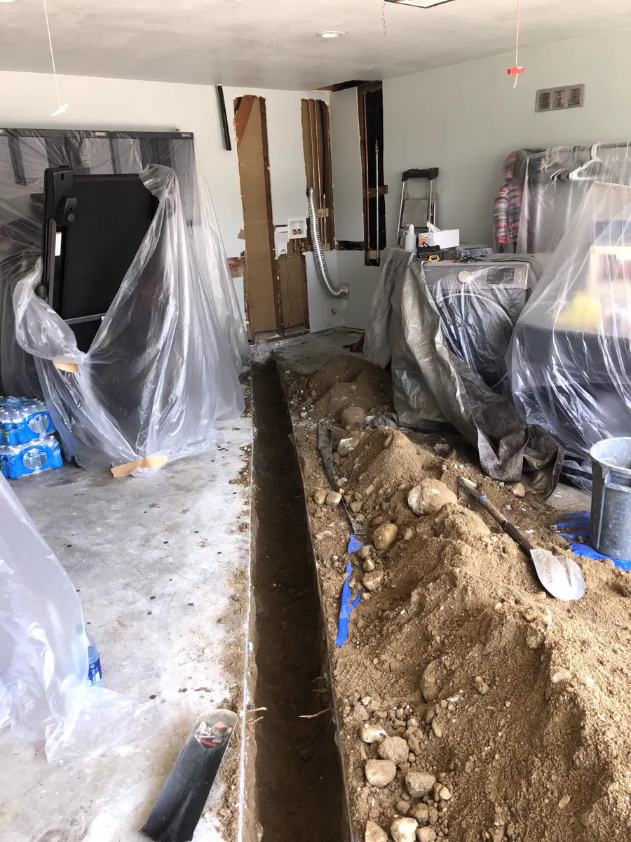 A trench cut through a floor slab with the rooms covered in plastic
