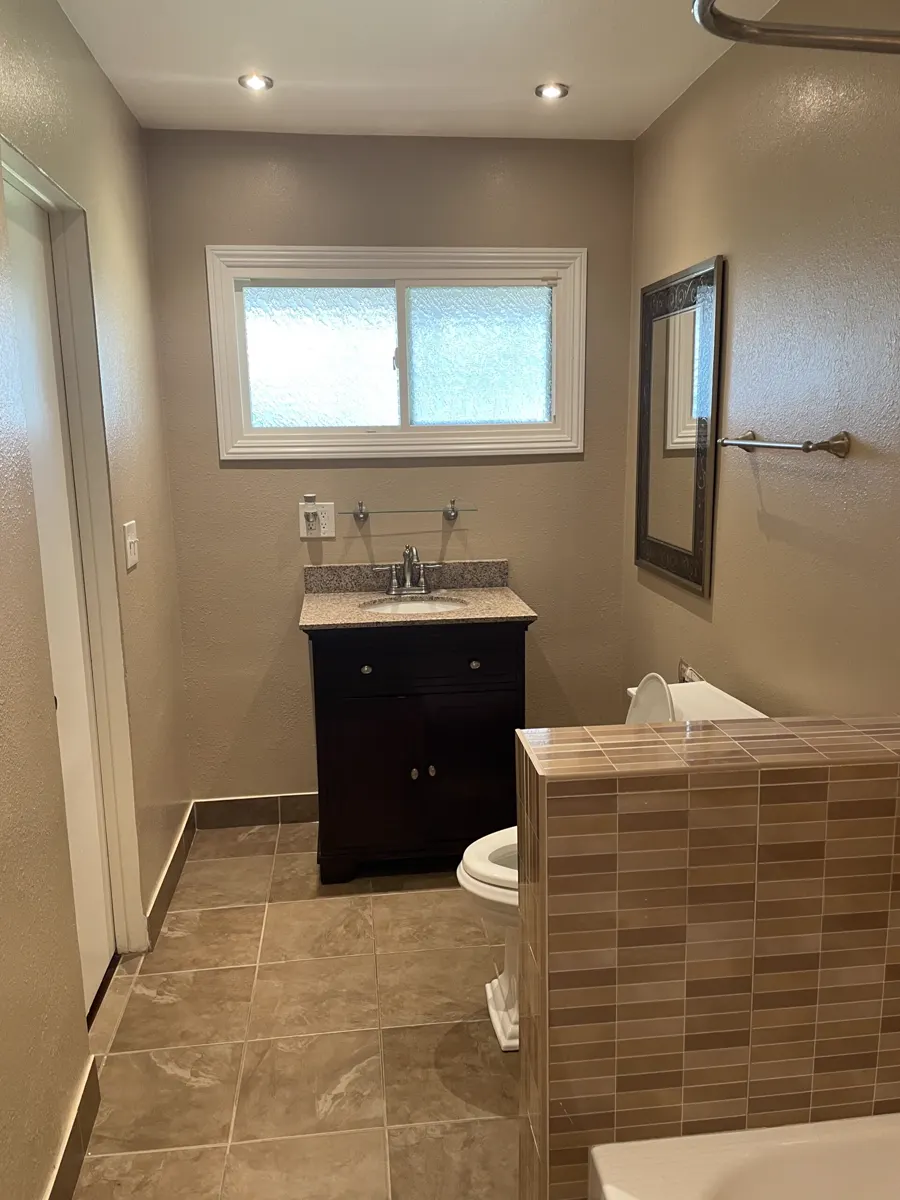 A dark vanity, a window and new floor tile in a small bathroom